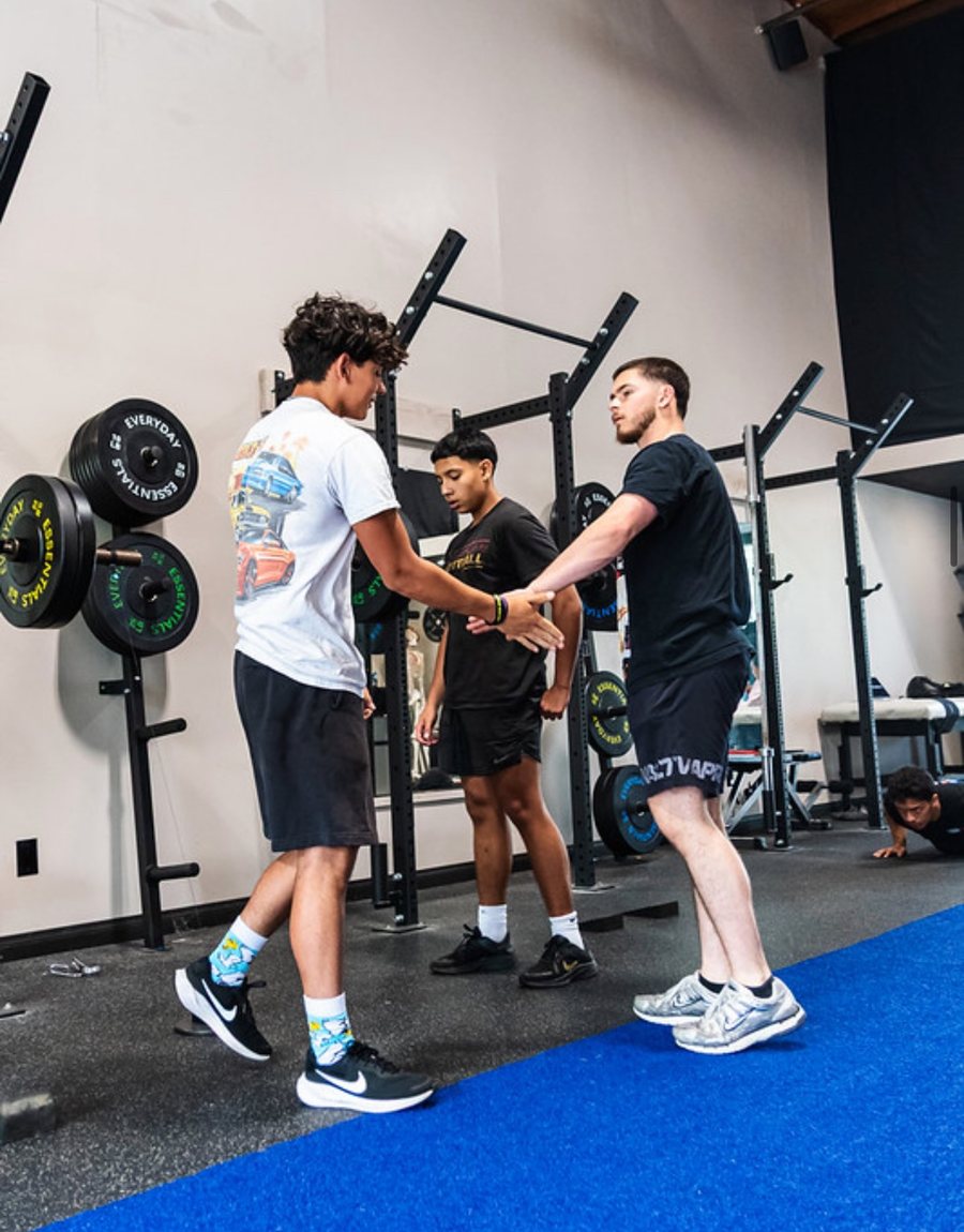 Kaiden coaching two athletes through a drill in the gym