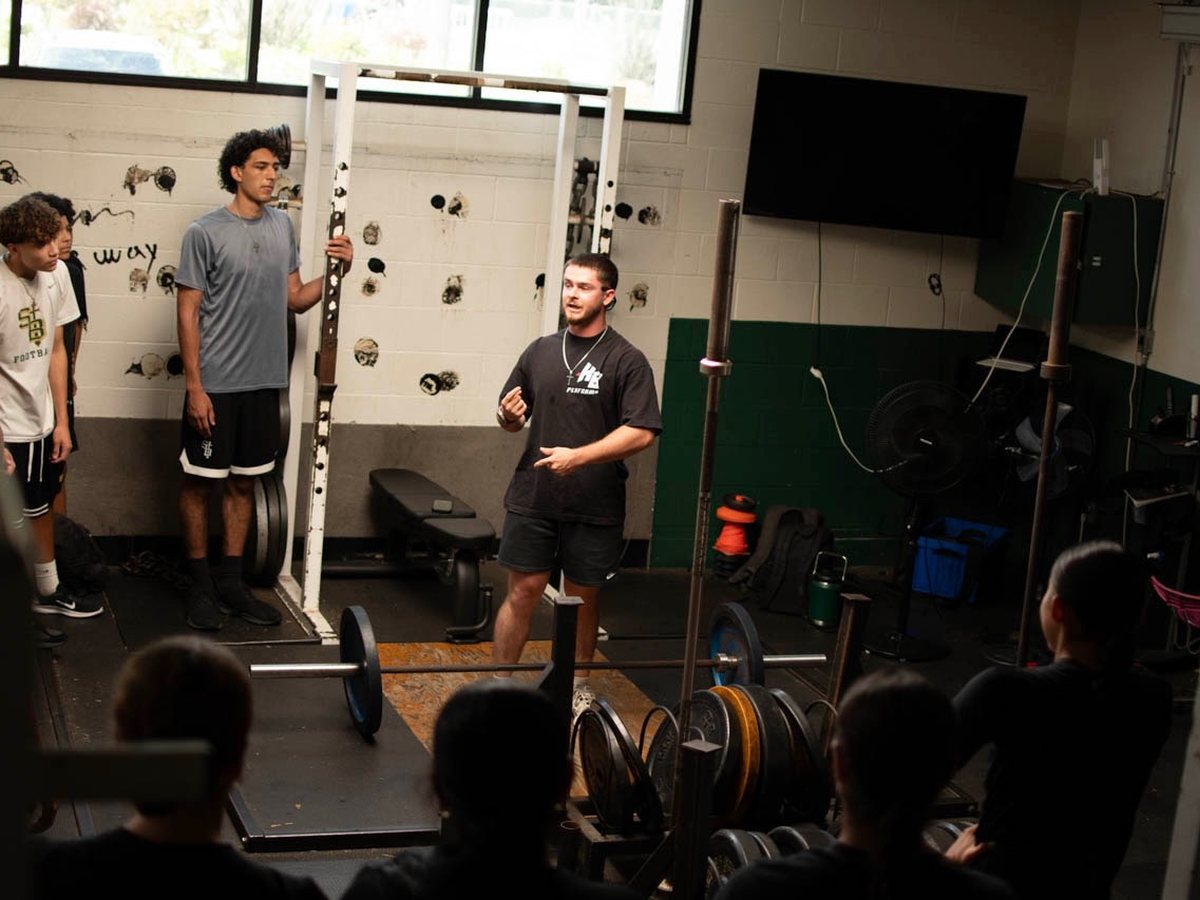 Kaiden coaching a group of athletes in the weight room